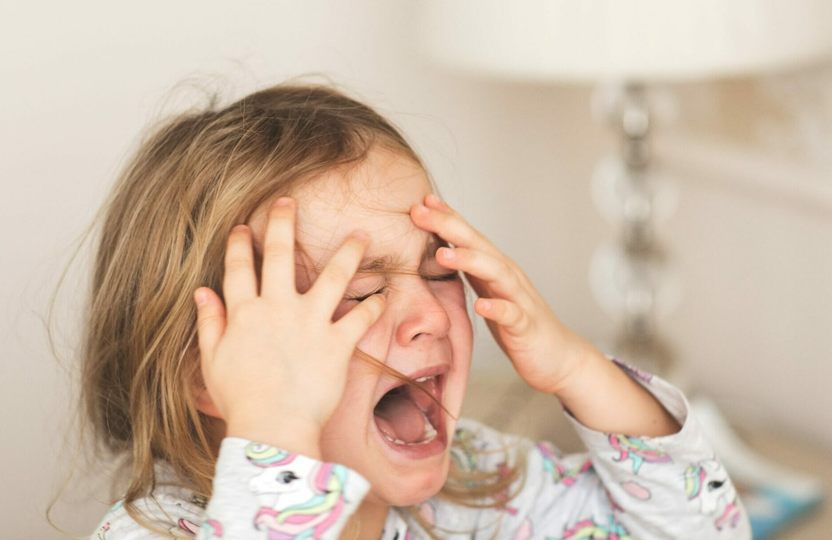 Young girl in pyjamas holding her head during a tantrum